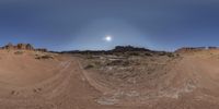 a 360 view photo of a desert with dirt roads in the foreground and the sun in the background