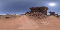 a 360 - view of some desert formations and mountains with rocks, dirt, grass, and a blue sky