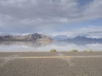 a view from a freeway looking across a desert landscape toward water and mountains, with clouds