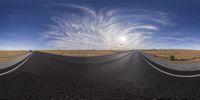 a long empty highway with white clouds flying in the sky in the middle of a desert