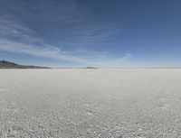 snow in the middle of the desert, looking across the wide open plains to a large mountain and horizon