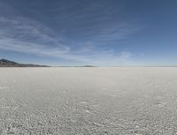 snow in the middle of the desert, looking across the wide open plains to a large mountain and horizon