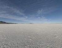 snow in the middle of the desert, looking across the wide open plains to a large mountain and horizon