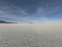 snow in the middle of the desert, looking across the wide open plains to a large mountain and horizon