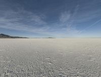 snow in the middle of the desert, looking across the wide open plains to a large mountain and horizon