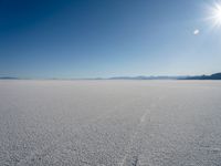 a man is walking across an empty field in the sun to cross with a horse