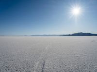 a man is walking across an empty field in the sun to cross with a horse