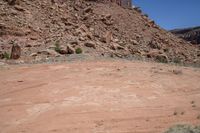 a dirt road through a desert plain with a mountain behind it and a clear blue sky in the background