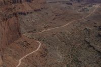 a dirt road is running near the cliffs and rocks in the desert area of a canyon