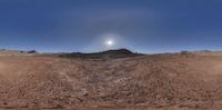 a view of a sky and some mountains from a fish eye lensed image shows a barren hill on top