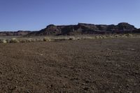 a dry landscape in the desert with arid areas in the background, with sparse green bushes and mountains