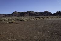 a dry landscape in the desert with arid areas in the background, with sparse green bushes and mountains