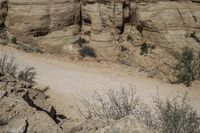 a motorcycle rider is riding down the road among large rocks and trees in a desert landscape