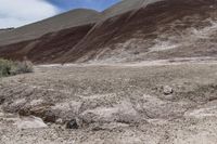 a person riding a motorcycle through a barren desert landscape with hills in the background,