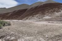 a person riding a motorcycle through a barren desert landscape with hills in the background,