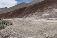 a person riding a motorcycle through a barren desert landscape with hills in the background,