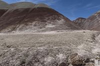 a person riding a motorcycle through a barren desert landscape with hills in the background,