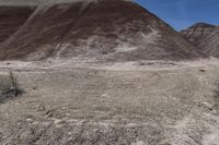 a person riding a motorcycle through a barren desert landscape with hills in the background,