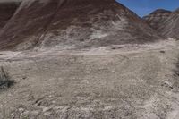 a person riding a motorcycle through a barren desert landscape with hills in the background,