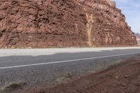 a motorcycle parked in front of a rocky cliff on a highway way between two road lanes