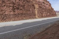 a motorcycle parked in front of a rocky cliff on a highway way between two road lanes