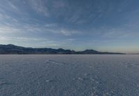 the ground with snow, mountains and a large sky in the background while viewed by a 3d person