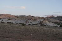 there is a small area of sand and a large hill in the background, with clouds flying by