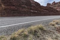 this is an image of an empty highway in the country side by side with rocks and mountains