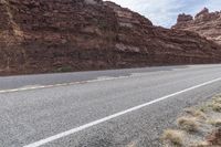 this is an image of an empty highway in the country side by side with rocks and mountains