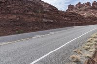 this is an image of an empty highway in the country side by side with rocks and mountains