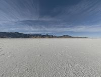 a sky view with a mountain range in the background at an expansive desert area that is nearly empty