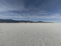 a sky view with a mountain range in the background at an expansive desert area that is nearly empty