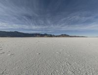 a sky view with a mountain range in the background at an expansive desert area that is nearly empty