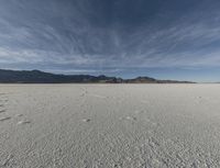 a sky view with a mountain range in the background at an expansive desert area that is nearly empty