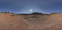 a desert landscape with sand, rocks and bushes under the full moon light, as a fish - eye lens