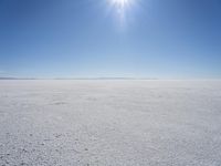 the sun is shining above a vast expanse of snow and ice, with snow covered ground in the background