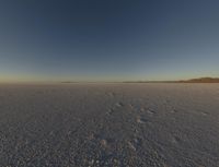 a plane flying through the sky on a plain with desert landscape in the background at sunset