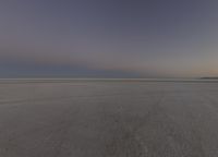 someone riding a motorcycle in a vast place at sunset, taking the photo in the dark