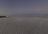 someone riding a motorcycle in a vast place at sunset, taking the photo in the dark