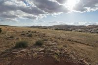 a view from a very small hill, looking towards the mountains and desert landscape with clouds