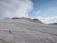 tracks and lines in the sand at a very large field with snow capped hills in the background