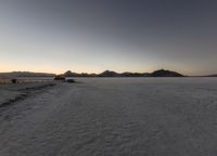 an empty desert area with mountains in the distance, at sunset, taken from a bird's eye view