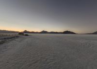 an empty desert area with mountains in the distance, at sunset, taken from a bird's eye view