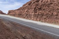 a dirt road leading through mountains and desert, along with a motorcycle parked next to it