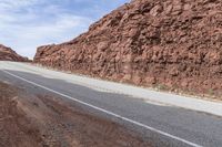 a dirt road leading through mountains and desert, along with a motorcycle parked next to it