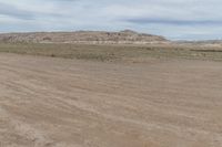 an empty field next to a big mountain with rocks in the background of the picture