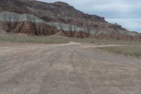 an empty field next to a big mountain with rocks in the background of the picture