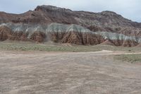 an empty field next to a big mountain with rocks in the background of the picture