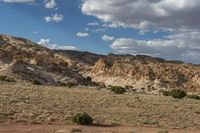 a truck driving in the desert under a partly cloudy sky, with mountains in the background