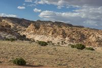 a truck driving in the desert under a partly cloudy sky, with mountains in the background